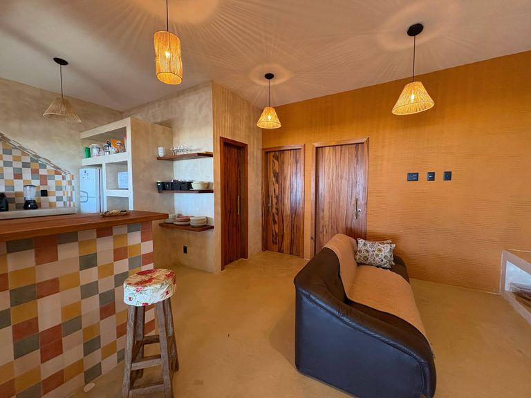 Sala da casa com bancada de azulejos coloridos, sofá e luminárias de fibra